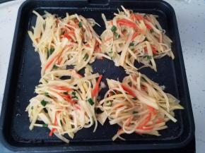 把搅拌好的土豆丝取出四小份，放在煎烤盘上，然后在上面撒上少许芝麻。