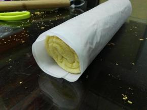 待蛋糕晾到手温时，就可以卷起来，表面盖上一张温纸，利用擀面杖来帮助卷起来，卷好之后放边上定型30分钟即可切块