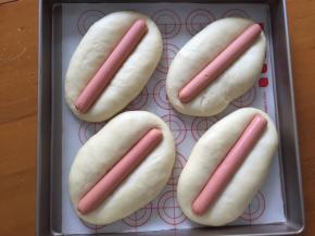 二次发酵完成后，将火腿肠放入面包中间，轻轻往下按，此时应该刷蛋液，我忘了