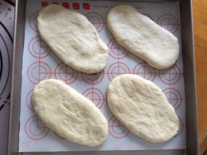 用擀面棒擀成牛舌状放入烤盘，放入烤箱二次发酵，下面放一碗热水