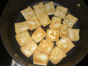 一面煎成金黄后翻面，将八角掰碎放在豆腐块之间的空隙中，继续煎制。