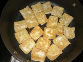 一面煎成金黄后翻面，将八角掰碎放在豆腐块之间的空隙中，继续煎制。