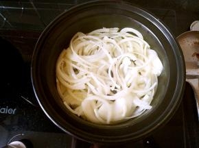 油热之后把圆葱丝倒进锅中，加入少许盐炒软。
