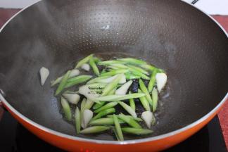 炒过腊肠的油锅，放入蒜白，爆炒片刻，放辣椒，放入蒜叶；