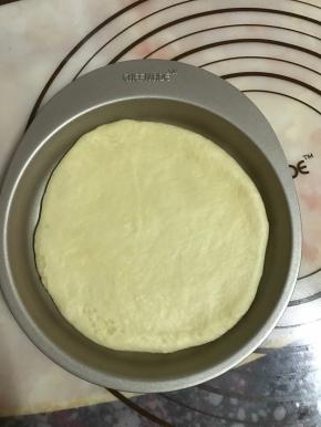 取一面团，用手压扁，擀成跟模具差不多大小的圆形，放入模具中。