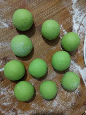 发酵好以后面团排气，揉至表面光滑切开面团切面无气孔，把绿色面团平均分成10份并揉圆