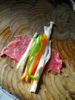 在牛肉片上放金针菇，大葱和青椒。