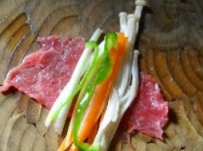 在牛肉片上放金针菇，大葱和青椒。