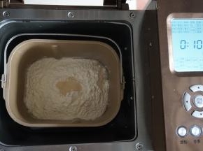 倒入面粉，在面粉顶端加入酵母，将面包桶放入到东菱1352-AE面包机里，启动面包机的和面程序10分钟