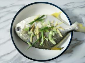 鱼身上两面抹适量盐，放上葱段姜丝，鱼肚里也塞一点