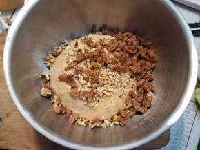 用水把葡萄干泡软，核桃切碎，倒入一次发酵好的面团，简单揉匀，压出面团气泡。