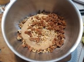 用水把葡萄干泡软，核桃切碎，倒入一次发酵好的面团，简单揉匀，压出面团气泡。