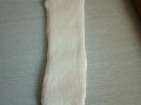 将第二次松弛好的面团再次擀成长舌状。翻面，由上往下卷起。