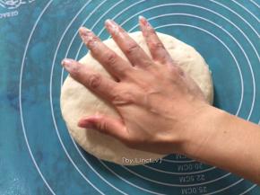 牛肉腌制时面团也差不多醒发好了。醒发后的面团会比之前大一些。将面板抹上一层油防粘，放上面团压扁