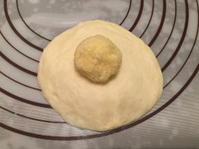 取一小份面团，包上椰蓉陷，收口捏紧