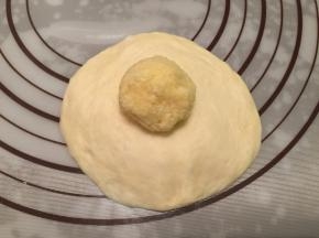 取一小份面团，包上椰蓉陷，收口捏紧