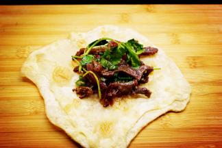 炒好牛肉、生菜放入煎好的饼上，卷起即可吃。