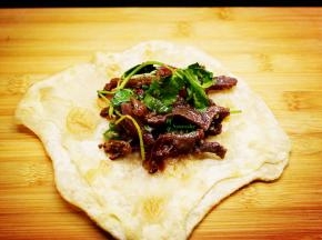 炒好牛肉、生菜放入煎好的饼上，卷起即可吃。