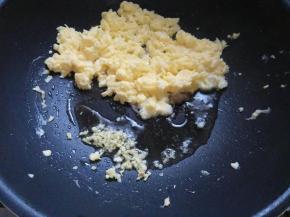 用筷子快速搅拌，蛋液成型推至锅边，下姜末爆香。