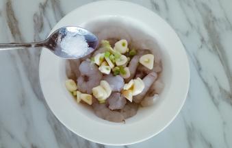 清理好的虾仁清洗干净，小葱和大蒜切碎放入小碟中，加入适量清水放置半小时，将葱蒜水放入虾仁中，加入小勺盐腌制半小时