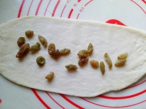 取一块面团，用擀面杖擀长舌状，放上葡萄干。