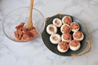 将肉馅填入口蘑中，尽量填得实一些。要高于口蘑。