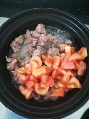 牛肉变白之后，加入三分之一的番茄一起翻炒。