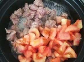 牛肉变白之后，加入三分之一的番茄一起翻炒。