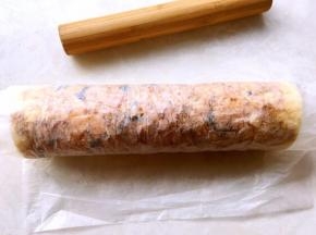 利用擀面杖向外卷起油纸，将蛋糕卷卷起来，卷好之后包裹油纸固定一下形状