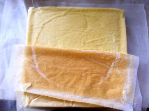 凉至不烫手时，另外铺一张油纸，将蛋糕卷倒扣在油纸上，揭下底部的油纸