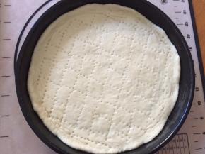 8寸披萨盘抹上玉米油，将饼皮放入披萨盘中，用叉子叉上小洞，这样避免饼皮在烤至过程中膨胀过高