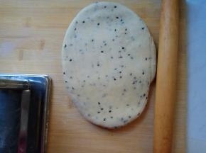 饧好的面团按扁，用擀面杖粗略擀成牛舌状。