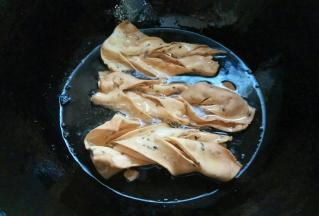 翻面后变色捞出控油。因为面片很薄，炸制时间很短。