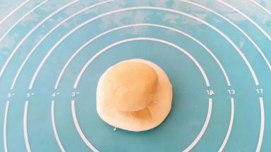 取一个水油皮按扁，包入油酥。