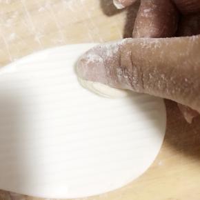 9.将小面块放在有纹路的工具上向前撮，(我用的是电饭锅的铲子，还可以用卷寿司的竹帘，陕西人是放到草帽边上撮的)