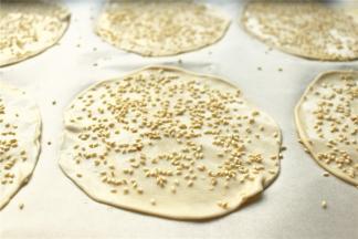 烤盘里垫油纸，放上薄饼，表面刷一点水，撒上白芝麻。
