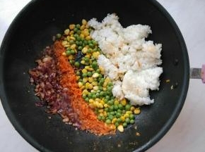 余油下姜末、洋葱粒炒香，再依次放入胡萝卜、青豆、玉米粒、米饭，翻炒均匀。
米饭下锅前，放入微波炉高火叮1分钟，这样米饭的水份蒸发一些，炒出来更干爽。