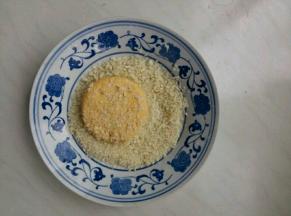 准备20g面包糠，将饼胚两面蘸点水，再在面包糠里裹匀，按紧，抖掉浮粉。