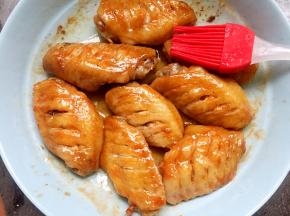 用硅胶刷将盘底的油刷在鸡翅上，让鸡翅变得油亮好看。