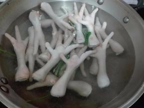 锅里放适量水烧开，加入适量葱和2片姜，放入鸡脚飞水。