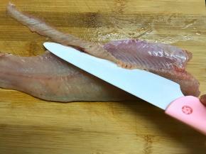 用刀片去鱼肚处的骨头。
