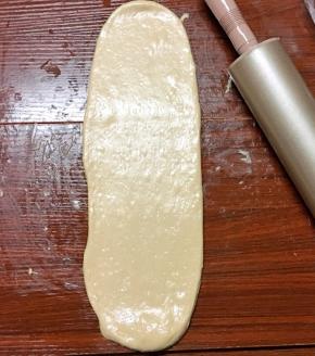 将其用手掌拍扁，再次擀开成牛舌状，边缘的气泡用手拍掉，翻面后自上而下卷起来
