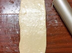 将其用手掌拍扁，再次擀开成牛舌状，边缘的气泡用手拍掉，翻面后自上而下卷起来