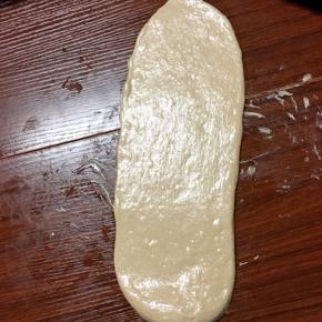 取一个松弛好的面团，光面朝下擀成椭圆