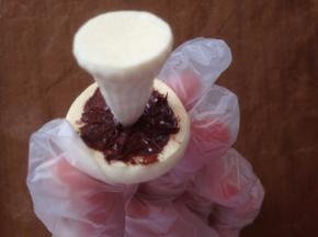 用融化的巧克力（白巧、黑巧都可以）抹在底部，将蘑菇柄尖的部位塞进去一点，待凝固