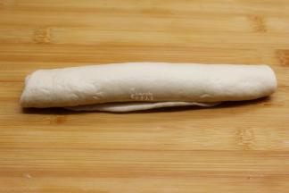 将面团从一头向另外一头卷起，要转紧；