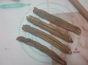 一只手拉着面条一端，另一只手按压切面，让面条变扁变长。依次弄完四份。