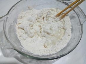 面粉分次浇入滚开的水，用筷子搅成絮状。