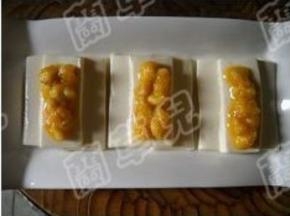 裹好蛋黄的鱼肉粒，放在蒸好的豆腐上。