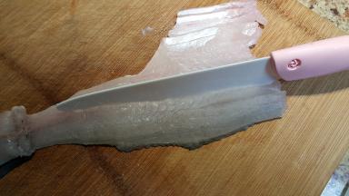 5.将鱼肉先竖着切开，奈瓷刀非常锋利，切鱼肉时要小心，不要把鱼皮切断哦。